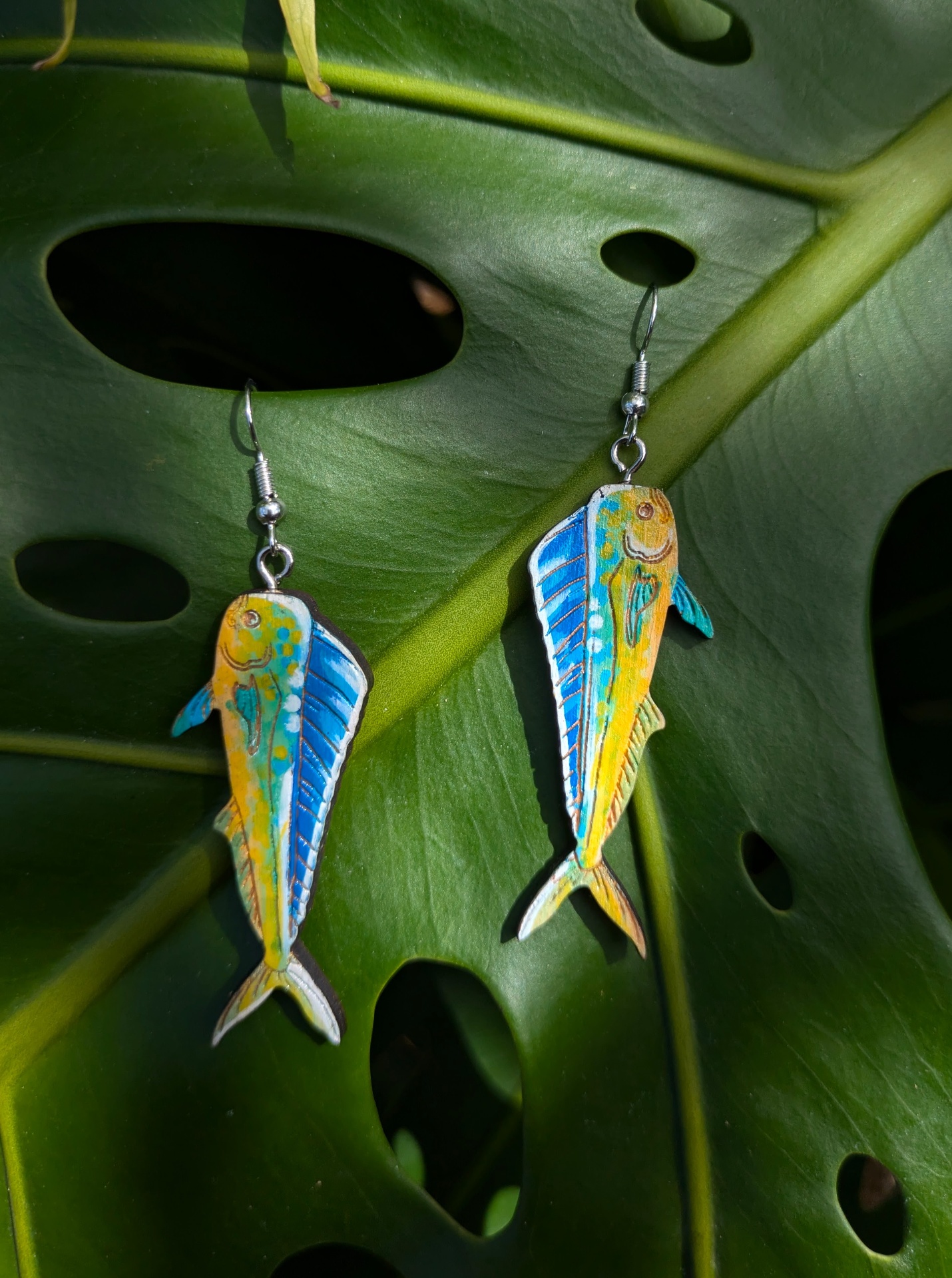 VibeHigh handmade jewelry — hand-painted fish earrings on a monstera leaf